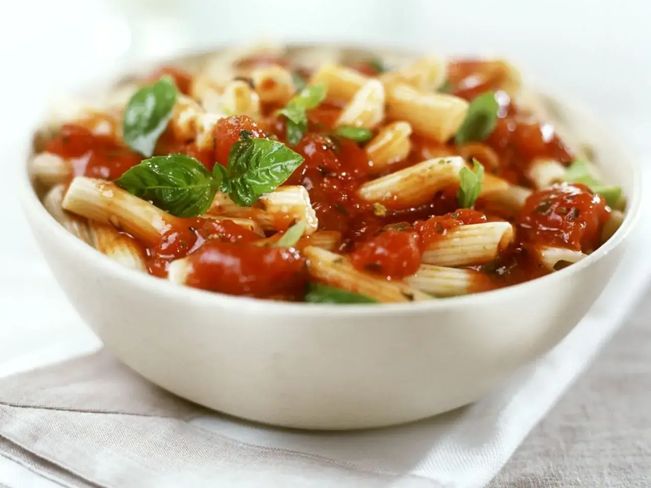 Sch&uuml;ssel mit Penne, &uuml;bergossen mit einer reichhaltigen, traditionellen Tomatensauce und garniert mit frischem Basilikum. Ein Genuss nach einem traditionellen Tomatensauce Rezept.