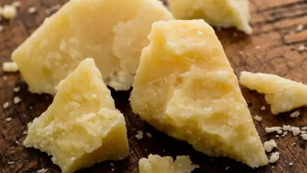 Stücke von Parmesankäse, die die authentische parmesan herkunft auf einem Holzbrett zeigen.